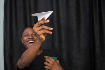 excited young black man holding a paper plane and passport
