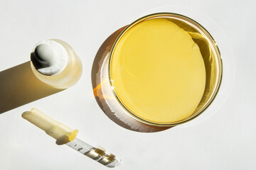 Petri dish. With yellow liquid. With solution. Cosmetic pipette. Comedy bottle. On a white background.