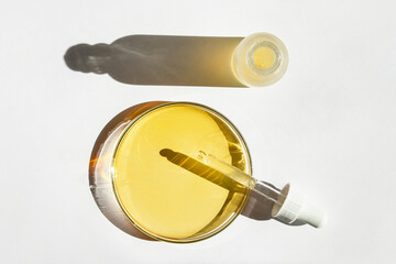 Petri dish. With yellow liquid. With solution. Cosmetic pipette. Comedy bottle. On a white background.