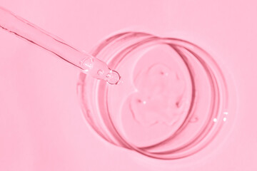 Petri dish. With transparent gel. The pipette lies. Cosmetic dispenser. On a pink background.
