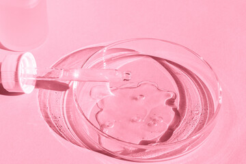 Petri dish. With transparent gel. With a pipette. Cosmetics bottle. On a pink background.