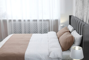 Comfortable bed and lamps in light room. Stylish interior