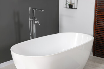 Stylish ceramic tub and modern tab in bathroom