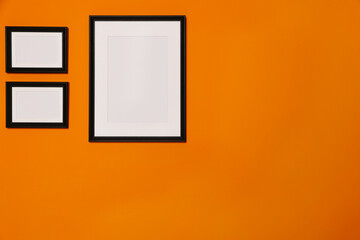 Empty frames hanging on orange wall. Mockup for design