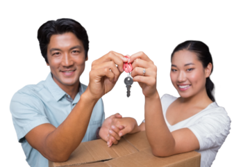 Happy couple holding house key and leaning on moving box