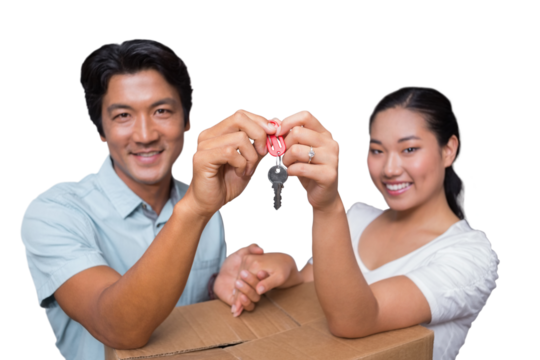 Happy couple holding house key and leaning on moving box