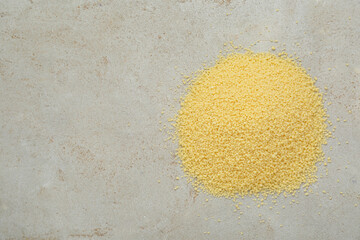Heap of raw couscous on light table, top view. Space for text