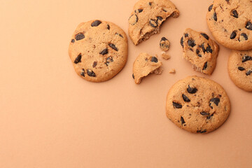 Many delicious chocolate chip cookies on beige background, flat lay. Space for text