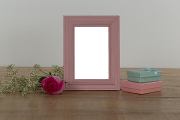 Obraz premium Photo frame, rose flower and gift boxes on a table