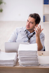 Naklejka premium Young male employee and too much work in the office