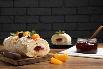 Tasty meringue roll with jam, tangerine slices and mint leaves on wooden table. Space for text