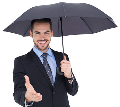 Happy businessman under umbrella offering handshake - Powered by Adobe
