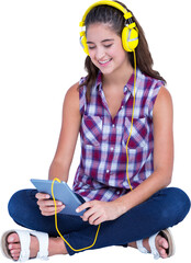 Woman listening music through headphones while holding digital tablet