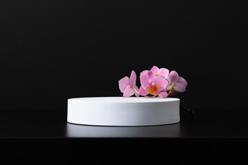 Obraz na płótnie Canvas White round podium pedestal cosmetic beauty product goods branding design presentation empty mockup on black background with shadows and beautiful pink orchid flowers cosmetic mockup