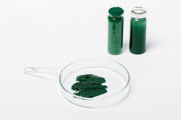 Spirulina mask or cream in a Petri dish. Cosmetic spatula. Spirulina powder in a jar. Spirulina oil...