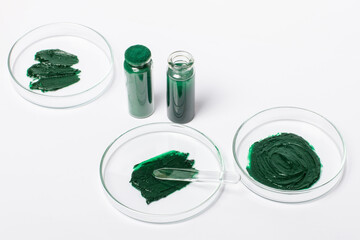 Petri dishes with maxa or spirulina cream. Spirulina powder in a jar. A solution or oil from...