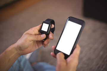 Cropped hands of man using smart watch and mobile phone