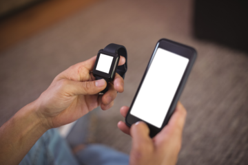 Cropped hands of man using smart watch and mobile phone
