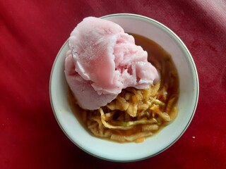 a rujak or spicy fruit salad dish topped with strawberry ice cream