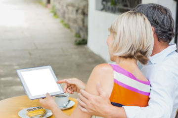Rear view of couple looking at digital tablet