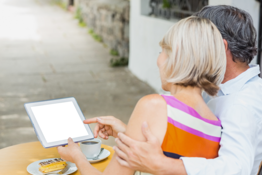 Rear view of couple looking at digital tablet