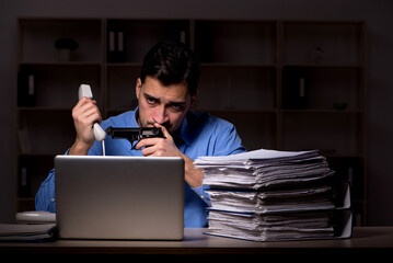 Young male employee working late in the office