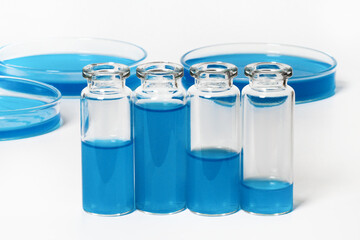 a set of flasks, jars for the laboratory with blue, blue liquid. Against the background of laboratory glassware. Petri dishes, flasks, test tubes. On a white, light background.