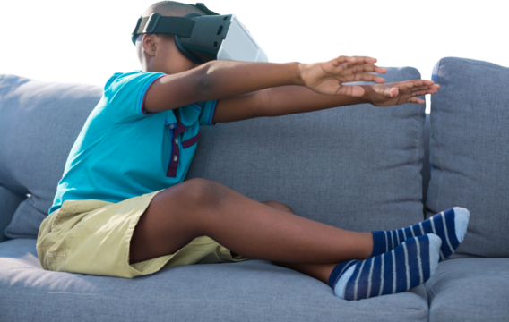 Boy using virtual reality simulator on couch