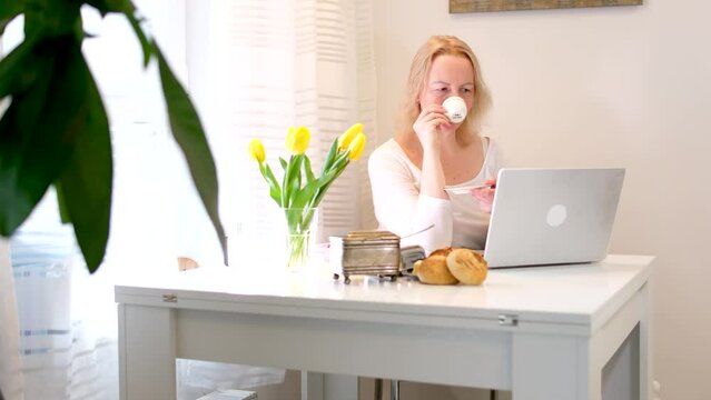 woman working and drinking coffee at white table with yellow tulips delicious breakfast lunch break good time communication relaxation freelance