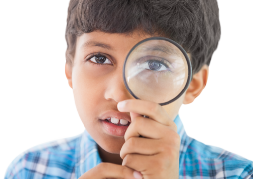 Cute boy looking through a magnifying glass