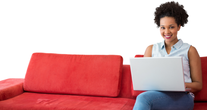 Smiling female college student using laptop while sitting on sofa