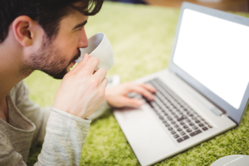 Man having coffee while using laptop