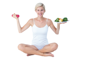 Attractive woman holding vegetables plate and dumbbell