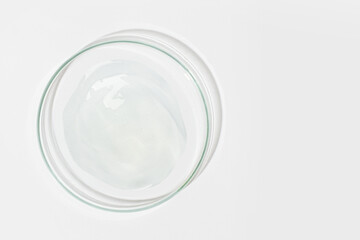 Petri dish on a light background. With a smear of clear gel. Cosmetic gel, lubricant, gel. View from above