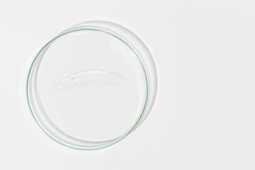 Petri dish on a light background. With a smear of clear gel. Cosmetic gel, lubricant, gel. View from above