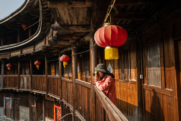 A tourist is taking photos for Fujian earthen buildings. Text on the door means 