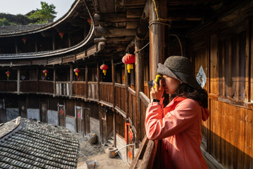 A tourist is taking photos for Fujian earthen buildings. Text on the door means 