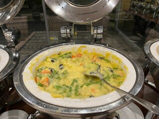 Vegetable au gratin being served in a chafing dish on the buffet table in a restaurant.