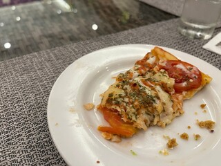 Top view one slice of pizza with tomato and cheese topping on a white plate.