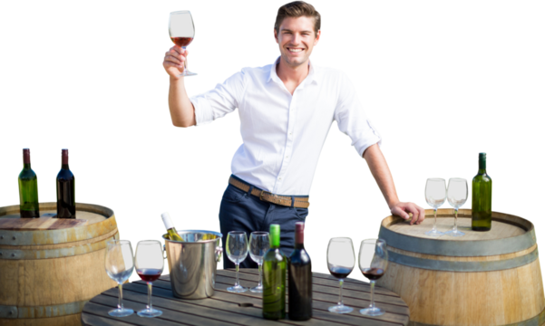 Portrait of smiling young man holding red wine glass by barrels