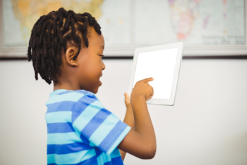 Boy pointing over digital tablet at classroom