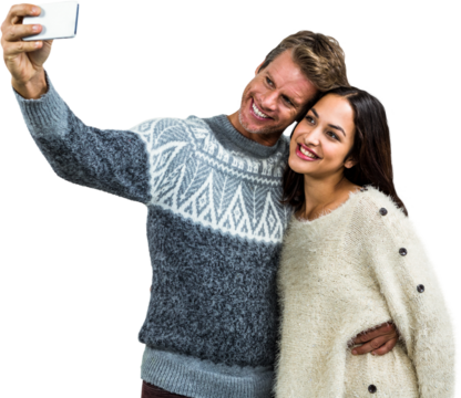 Cheerful young couple wearing warm clothing taking selfie