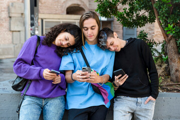 Friends using mobile phone while standing outdoors on the street.