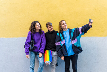 Young diverse friends taking selfies with a mobile phone outdoors.