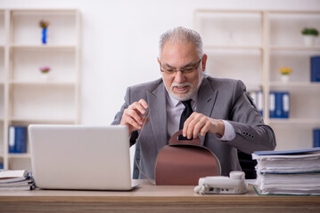 Naklejka premium Old male employee eating cake in the office