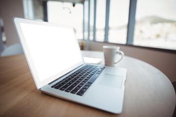 Fototapeta premium Laptop by coffee cup on table