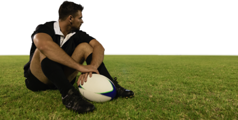 Rugby player sitting on the field with football.