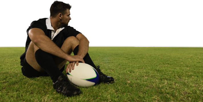 Rugby player sitting on the field with football. - Powered by Adobe