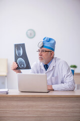 Old male docror otolaryngologist working in the clinic