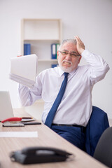 Fototapeta premium Old male employee working in the office